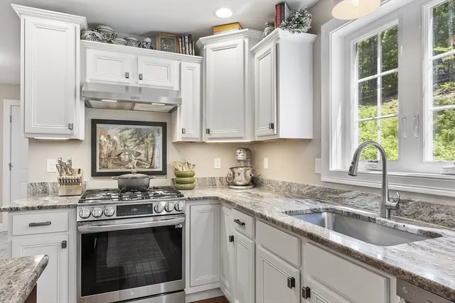 a kitchen with granite countertop a sink stainless steel appliances and cabinets