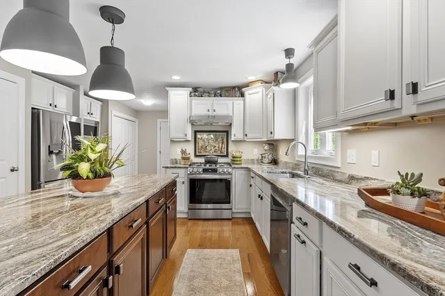 a kitchen with stainless steel appliances granite countertop a sink a stove and a wooden floors