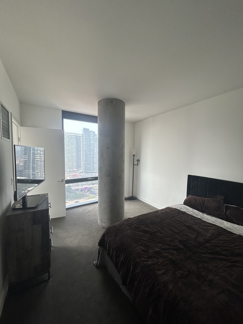 730 West Couch Place, Unit 1805 Chicago, IL 60661 - Photo 4 of 9 a bedroom with a bed and wooden floor