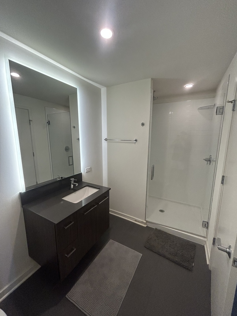730 West Couch Place, Unit 1805 Chicago, IL 60661 - Photo 5 of 9 a bathroom with a granite countertop sink a mirror and shower