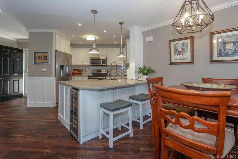 1114 Torrence Circle, Unit 1114 Davidson, NC 28036 - Photo 2 of 29 a kitchen with stainless steel appliances kitchen island granite countertop a table chairs in it and wooden floors