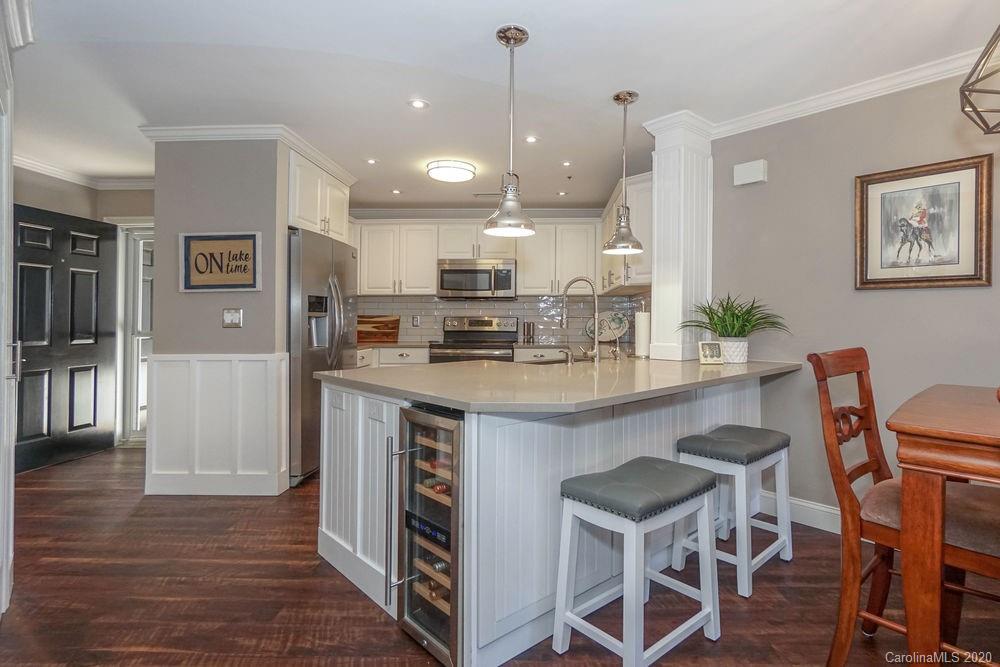 1114 Torrence Circle, Unit 1114 Davidson, NC 28036 - Photo 3 of 29 a kitchen with kitchen island granite countertop wooden floors and refrigerator