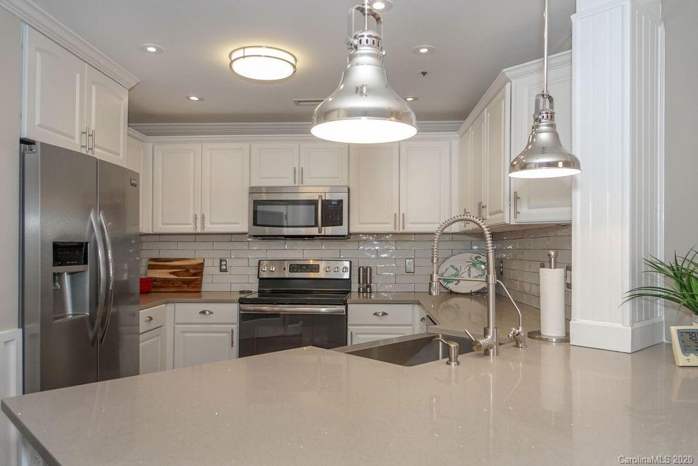 1114 Torrence Circle, Unit 1114 Davidson, NC 28036 - Photo 6 of 29 a kitchen with stainless steel appliances kitchen island granite countertop a refrigerator a stove a sink dishwasher and white cabinets with wooden floor