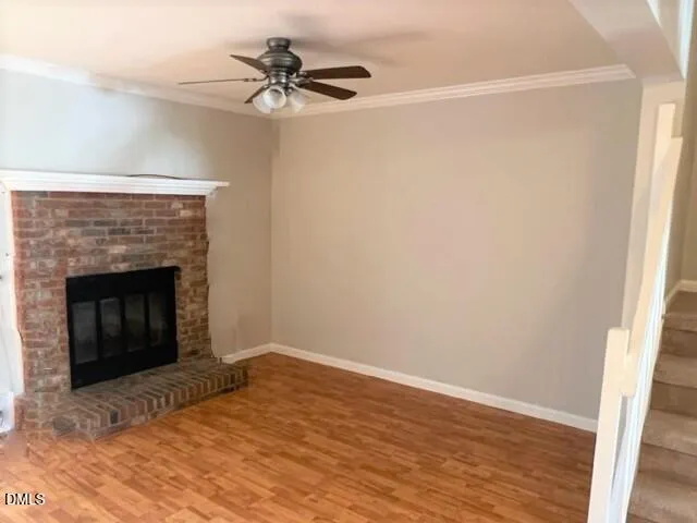 a view of empty room with wooden floor and a fireplace