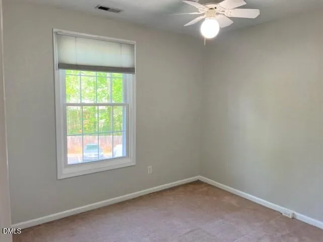 an empty room with a window and a fan