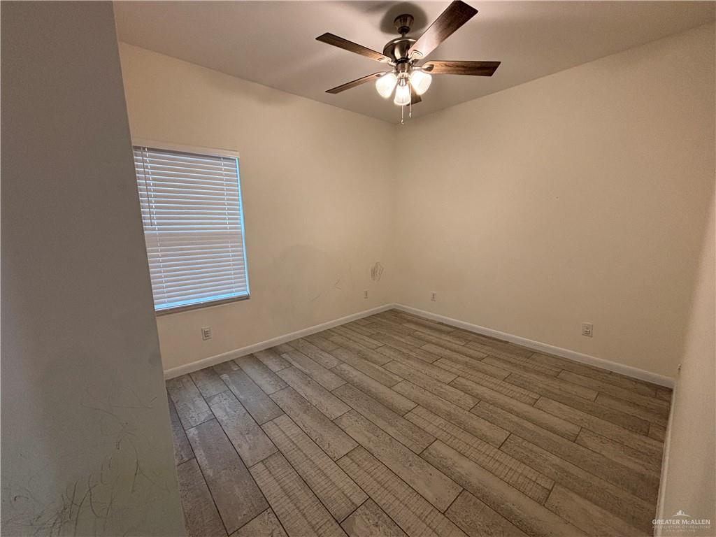 212 Lauryn Drive, Unit 3 San Juan, TX 78589 - Photo 15 of 27 an empty room with wooden floor chandelier fan and windows