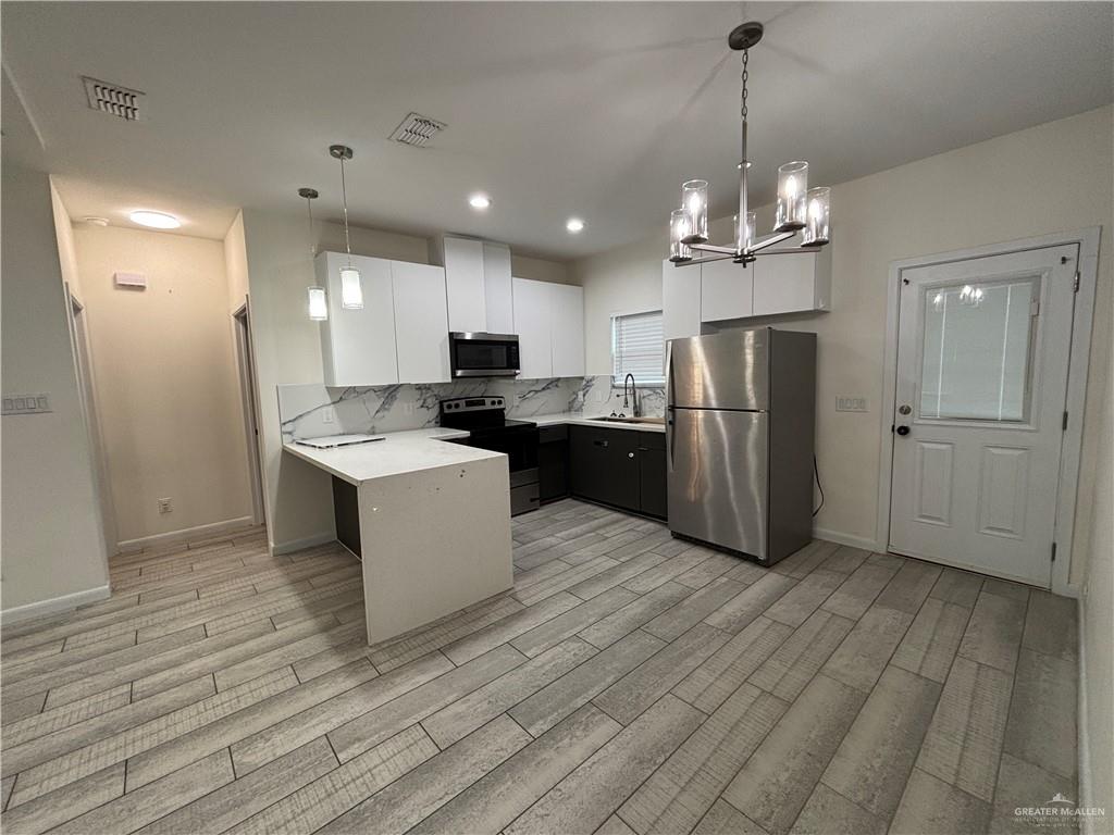 212 Lauryn Drive, Unit 3 San Juan, TX 78589 - Photo 2 of 27 a large kitchen with stainless steel appliances granite countertop a refrigerator a sink dishwasher a stove and a dining table with wooden floor