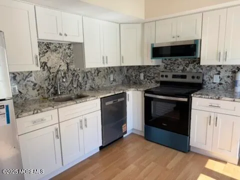 a kitchen with granite countertop white cabinets and stainless steel appliances