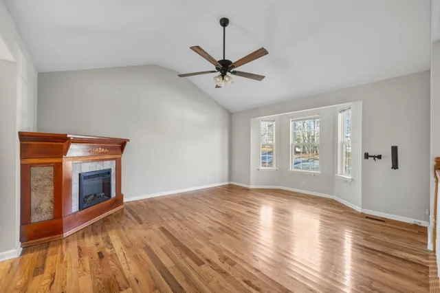 a view of an empty room with window and wooden floor