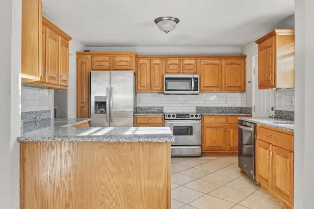 a kitchen with stainless steel appliances granite countertop a stove a sink and a microwave