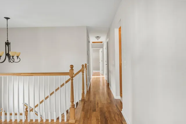 a view of a hallway with wooden floor and staircase