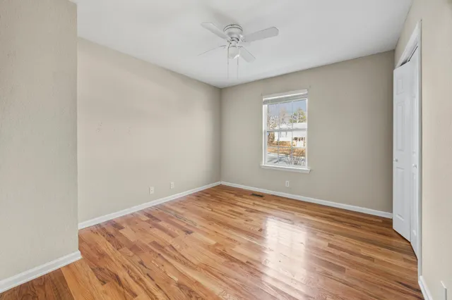 a view of empty room with wooden floor and fan