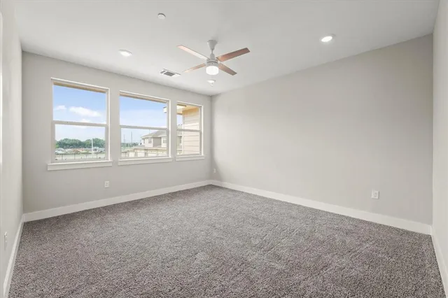 an empty room with windows and ceiling fan