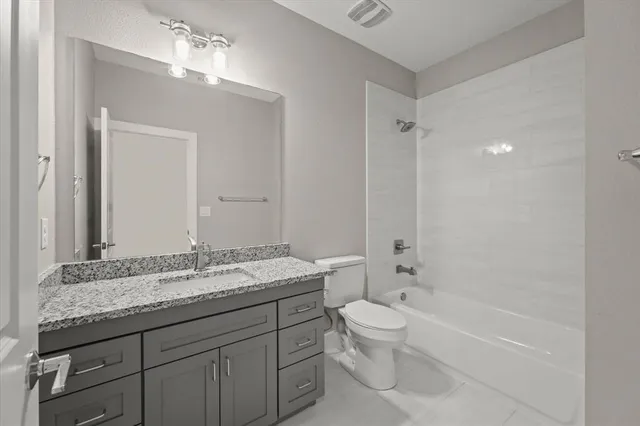 a bathroom with a granite countertop sink a toilet and bathtub
