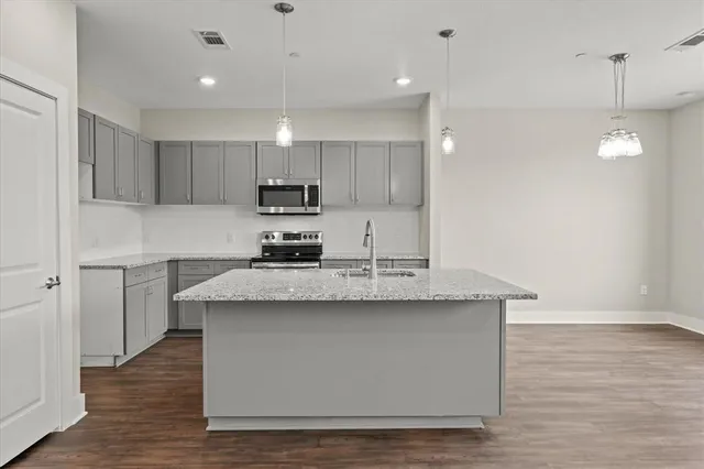 a kitchen with kitchen island stainless steel appliances a sink a stove a refrigerator and cabinets