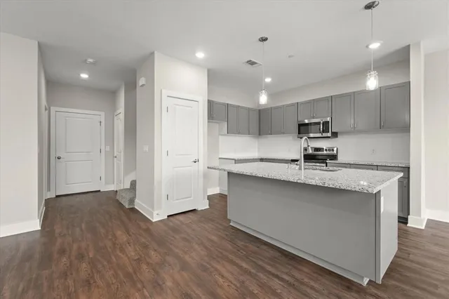 a kitchen with stainless steel appliances granite countertop a sink a stove a refrigerator and cabinets