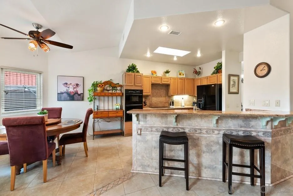 14420 Silver Heights Road Poway, CA 92064 - Photo 35 of 73 a kitchen with stainless steel appliances kitchen island granite countertop a table chairs in it and wooden floors