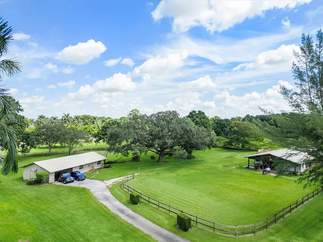 an aerial view of a house with swimming pool garden and trees