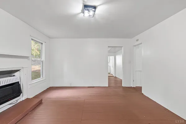 a view of an empty room with a fireplace and a window