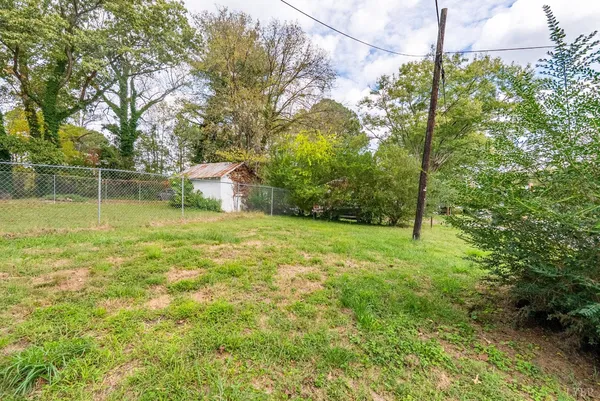 a white house that has a small yard and large trees