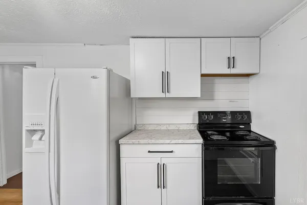 a kitchen with white cabinets and refrigerator