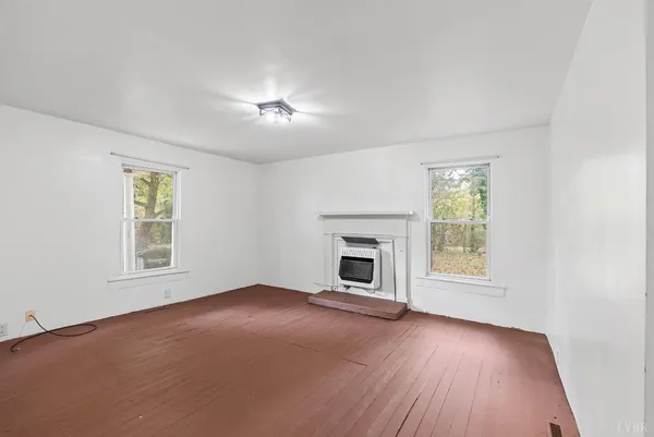 an empty room with windows fireplace and wooden floor