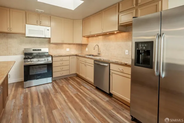a kitchen with stainless steel appliances granite countertop a stove a sink and a refrigerator
