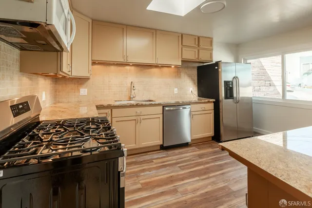 a kitchen with stainless steel appliances granite countertop a stove a sink dishwasher and a refrigerator