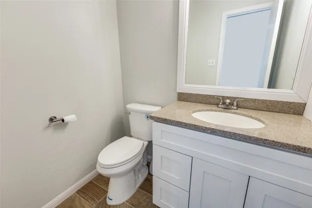 a bathroom with a granite countertop toilet sink and mirror
