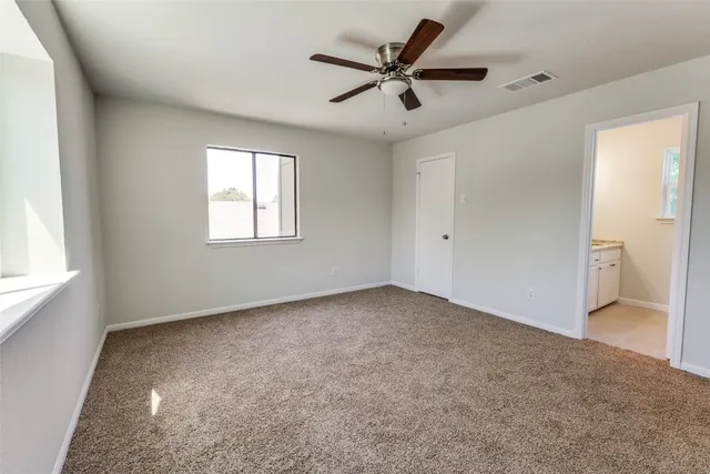 an empty room with a window and a fan