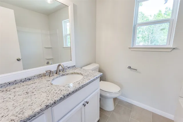 a bathroom with a granite countertop sink a toilet and a mirror
