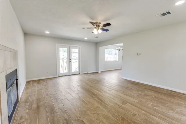 a view of an empty room with a window and wooden floor