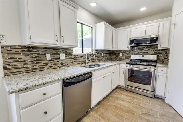 a kitchen with granite countertop a sink stainless steel appliances and cabinets