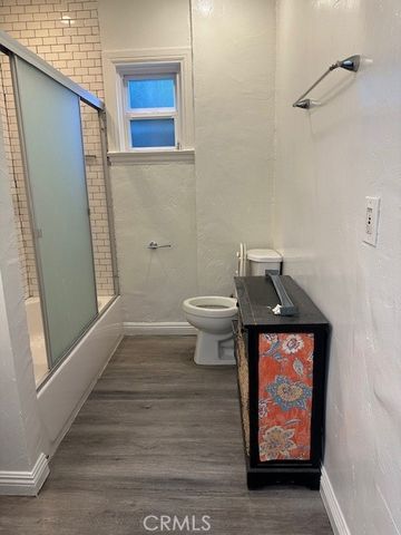 a view of a hallway with wooden floor and paintings on the wall