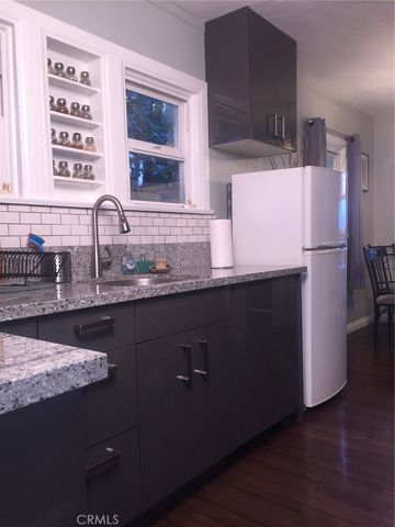 a kitchen with granite countertop a refrigerator a sink and wooden cabinets