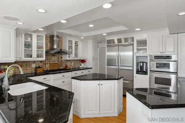 a kitchen with stainless steel appliances kitchen island granite countertop a stove a sink and a refrigerator