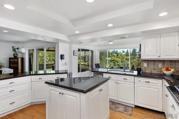 a kitchen with white cabinets and a large window