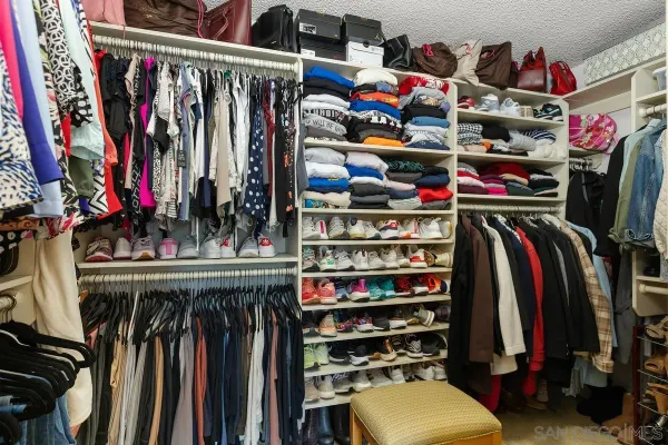 a view of walk in closet with clothes and shoes