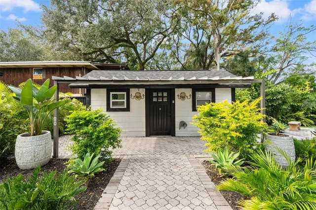 a view of backyard with table and chairs potted plants and large tree