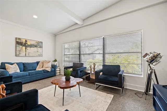 a living room with furniture kitchen view and a large window