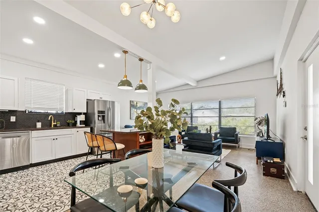 a kitchen with stainless steel appliances kitchen island granite countertop a stove a sink a refrigerator a dining table and chairs