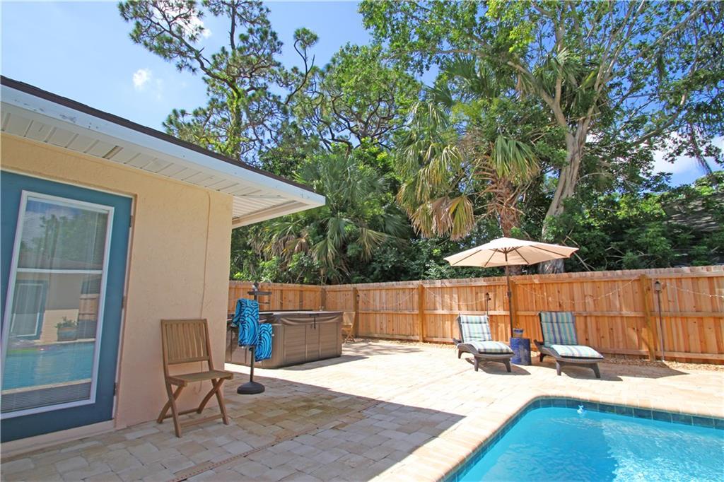 783 Northwest Spruce Ridge Drive Stuart, FL 34994 - Photo 22 of 29 a patio with a table and chairs under an umbrella with a barbeque