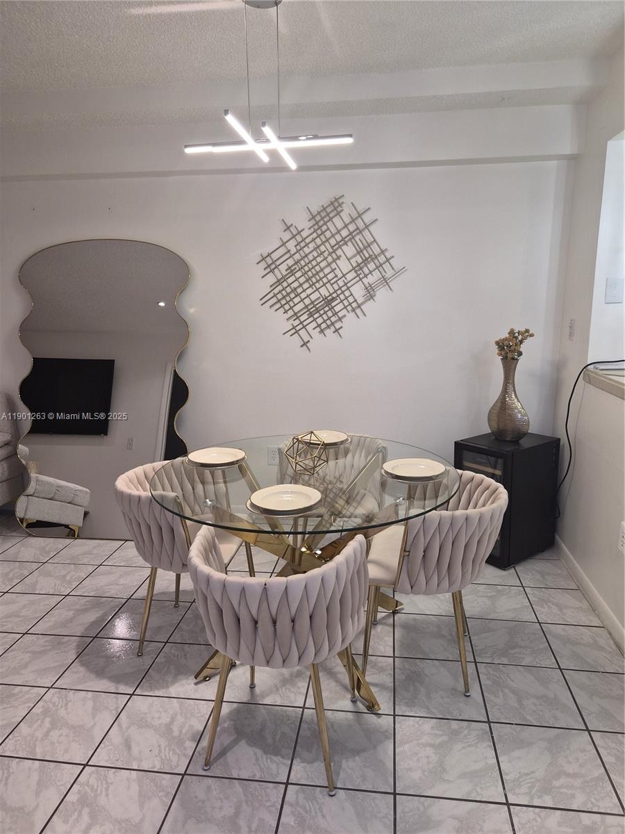 201 180th Drive, Unit 411 Sunny Isles Beach, FL 33160 - Photo 8 of 53 a view of a dining room with furniture and chandelier