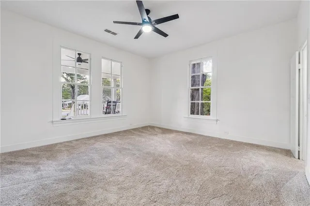 an empty room with windows and ceiling fan