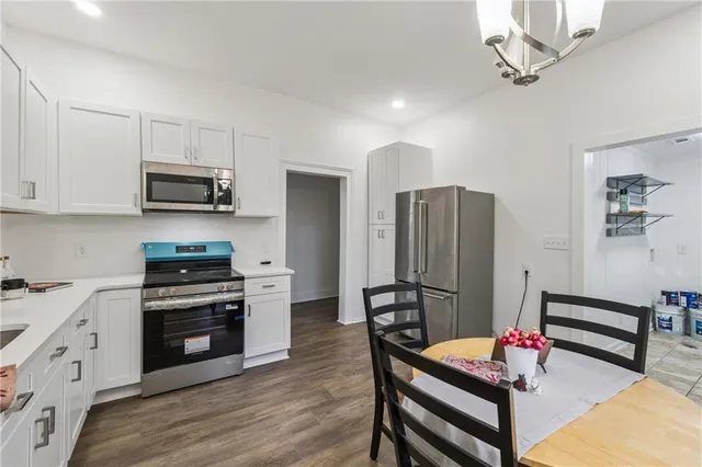 a kitchen with stainless steel appliances kitchen island granite countertop a refrigerator a stove a microwave oven a sink with island and chairs