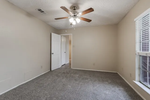 an empty room with ceiling fan and window