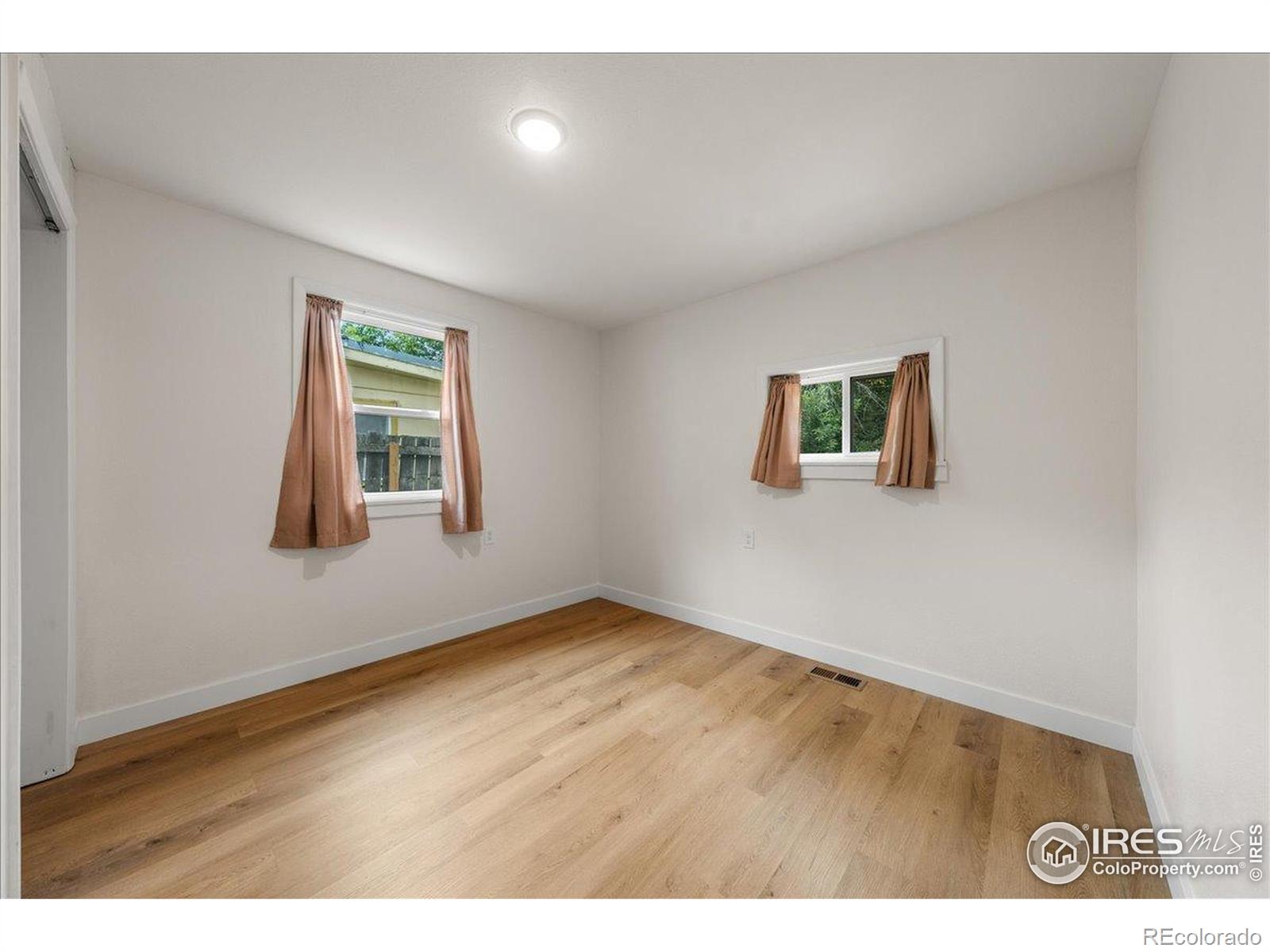 727 Baker Street Longmont, CO 80501 - Photo 17 of 25 a view of an empty room with window and wooden floor