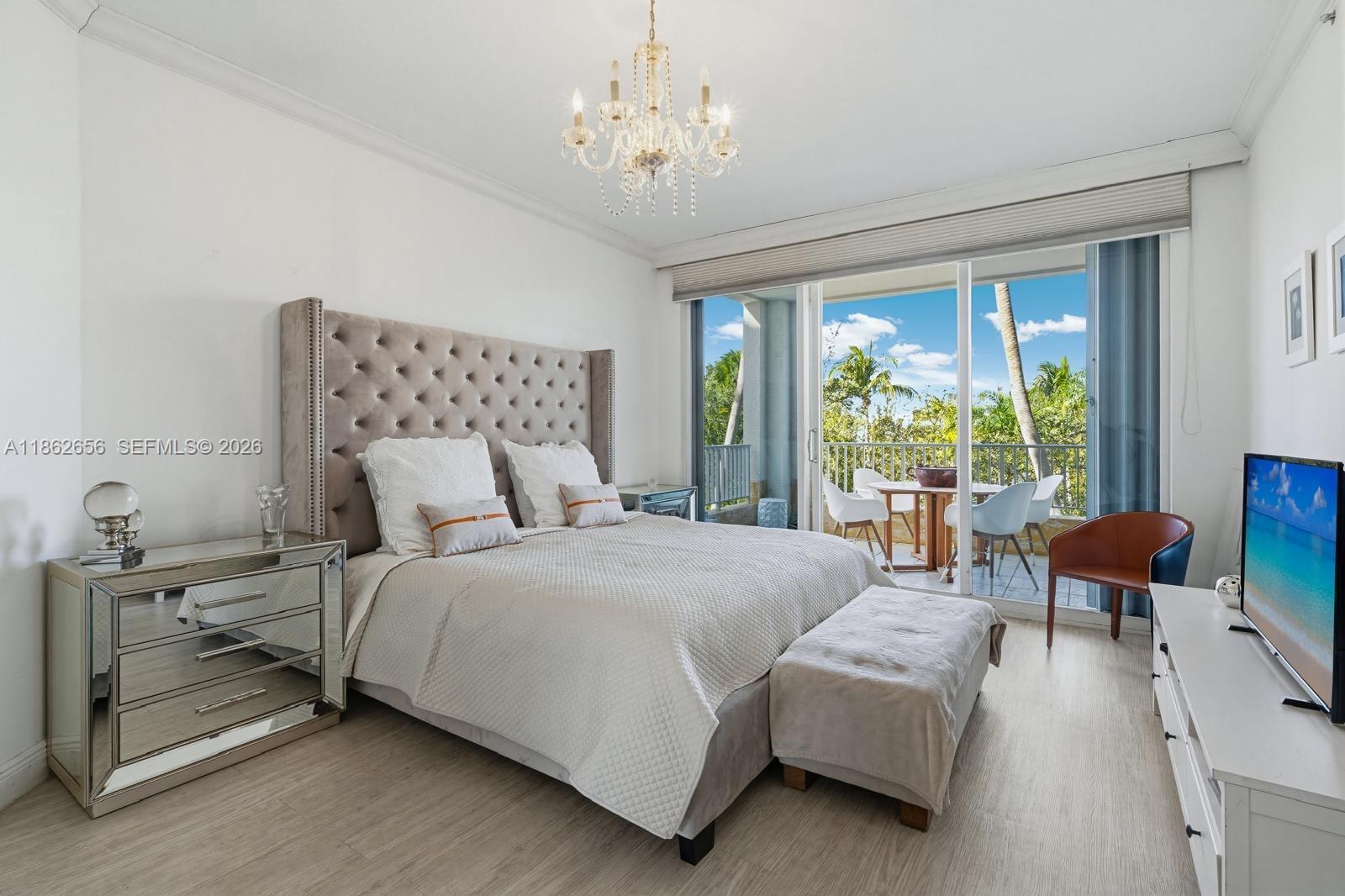 701 Crandon Boulevard, Unit 302 Key Biscayne, FL 33149 - Photo 12 of 26 a bedroom with a bed and a chandelier