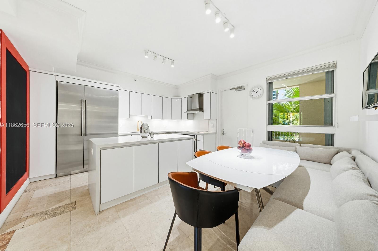 701 Crandon Boulevard, Unit 302 Key Biscayne, FL 33149 - Photo 18 of 26 a kitchen with a dining table chairs refrigerator and sink