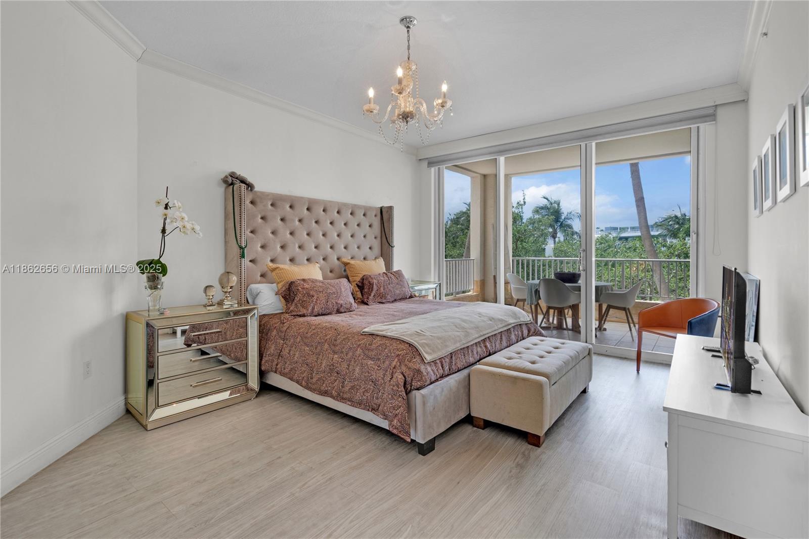 701 Crandon Boulevard, Unit 302 Key Biscayne, FL 33149 - Photo 25 of 46 a spacious bedroom with a bed and a chandelier